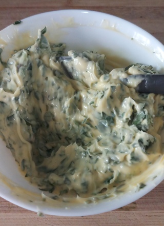 Basil Butter mix in blue container on copper tray with some basil leaves.