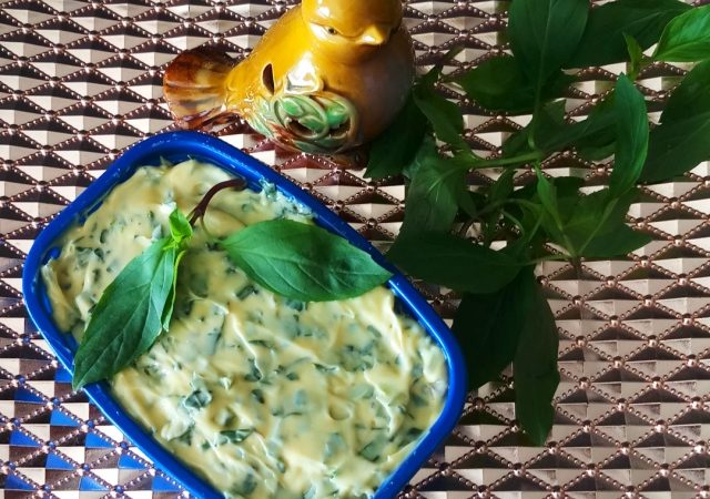 Basil Bliss Butter: Homemade Gourmet Delight keep in blue container on copper tray with some basil leaves.