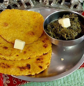 A bowl of Sarson ka Saag served with makki di roti, showcasing the vibrant green colors of the dish.

