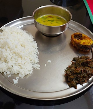 A colourful plate of Healthy Mixed Saag, showcasing a medley of white rice, fried fish and yellow dal.
