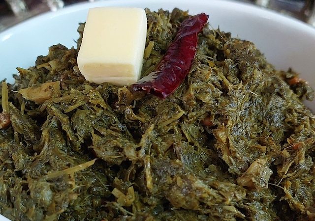 Sarson ka Saag in white bowl showcasing the vibrant green colours of the dish.