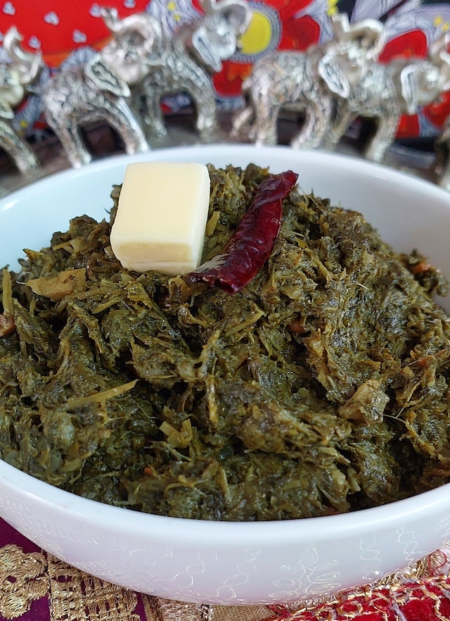 Sarson ka Saag in white bowl showcasing the vibrant green colours of the dish.

