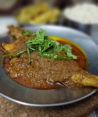 A tantalizing plate of spicy Bhola Mach recipe, garnished with fresh cilantro leaves, served with steamed rice on the side.