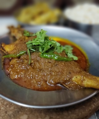  A tantalizing plate of spicy Bhola Mach recipe, garnished with fresh cilantro leaves, served with steamed rice on the side.