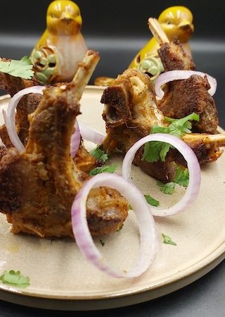 A plate of golden-brown mutton chops served with onion rings.