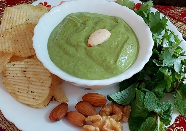 A bowl filled with vibrant green makhmali chutney garnished with soaked almond.