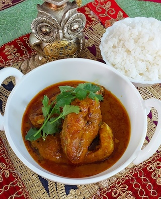 A bowl of delicious Katla Fish Jhal, a traditional Bengali fish curry, garnished with fresh coriander leaves.