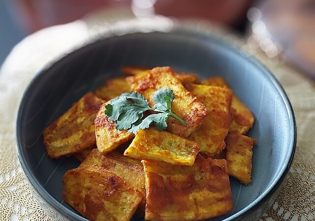 Crispy raw banana fritters (kachche kele ke pakode) served on a plate with green chutney and hot masala chai.