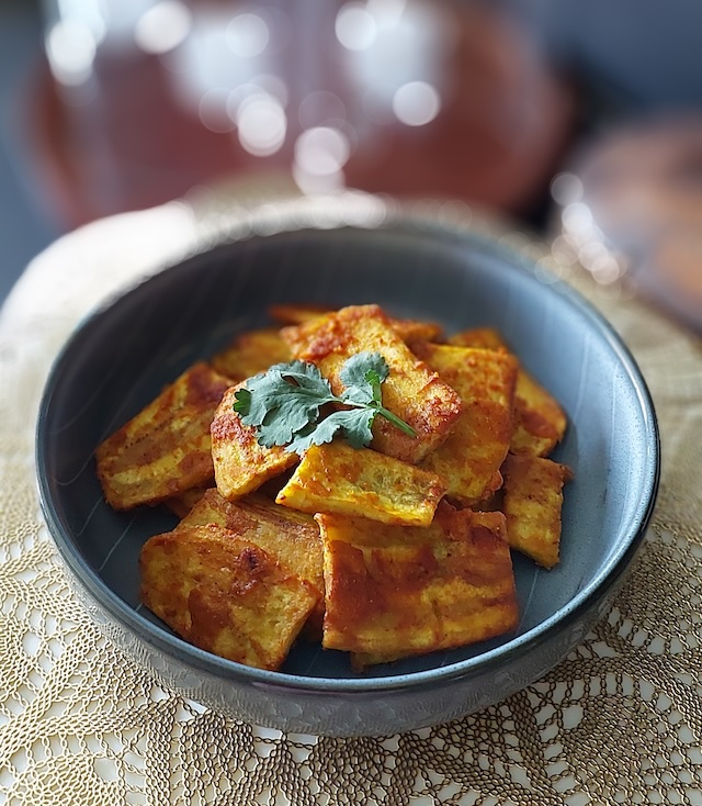 Crispy raw banana fritters (kachche kele ke pakode) served on a plate with green chutney and hot masala chai.