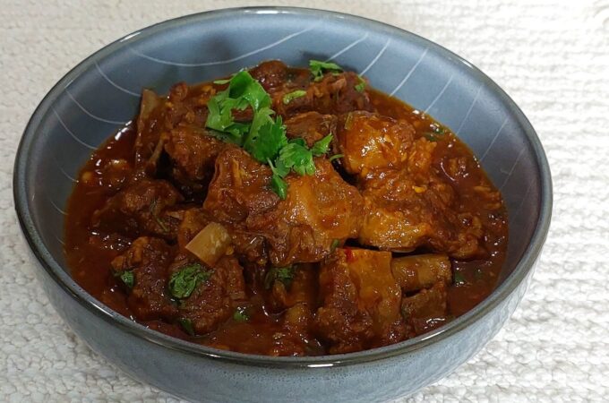 Simple mutton curry recipe in a bowl garnished with coriander leaves